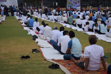 Yeni Delhi, Hindistan, 21 Haziran 2025 - Uluslararası Yoga Günü 'nde Delhi' deki Yamuna Spor Kompleksi 'nde grup Yoga egzersiz oturumu, kriket stadyumunda yoga sınıfına katılan büyük bir grup yetişkin