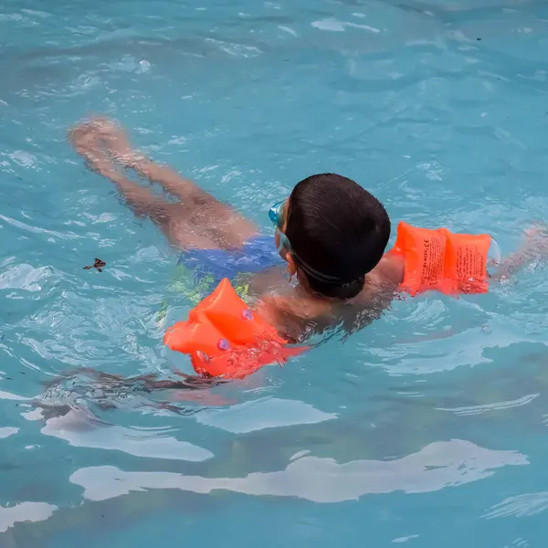 Havuzda yüzen mutlu Hintli çocuk, sıcak yaz tatillerinde hava tüpüyle birlikte yüzen çocuk, büyük bir havuzda yüzen çocuk..