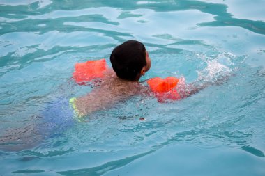 Havuzda yüzen mutlu Hintli çocuk, sıcak yaz tatillerinde hava tüpüyle birlikte yüzen çocuk, büyük bir havuzda yüzen çocuk..