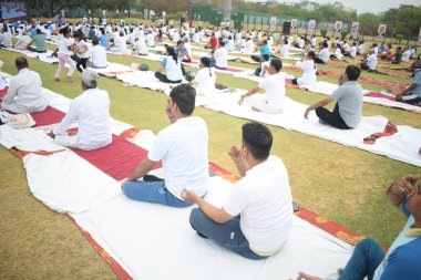Yeni Delhi, Hindistan, 21 Haziran 2025 - Uluslararası Yoga Günü 'nde Delhi' deki Yamuna Spor Kompleksi 'nde grup Yoga egzersiz oturumu, kriket stadyumunda yoga sınıfına katılan büyük bir grup yetişkin