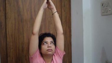 Evde yoga yapan genç Hintli bir kadın çevrimiçi yoga seansında güzel bir kız temel yoga pozisyonunda Asyalı bir kadın kapalı alanda yoga yapıyor. 