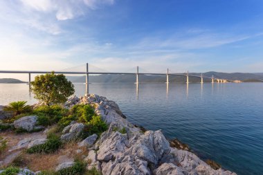 Beautiful modern bridge over the sea on Peljesac in Croatia. In the foreground houses and in the background the Peljesac mountain