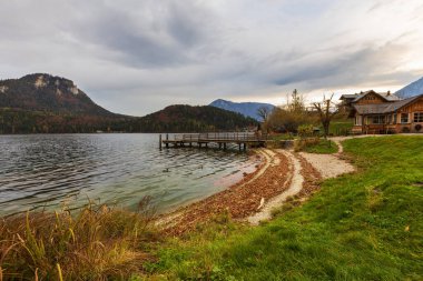 Shore of Lake Altausee in Austria, small wooden pier with beautiful autumn sky. clipart