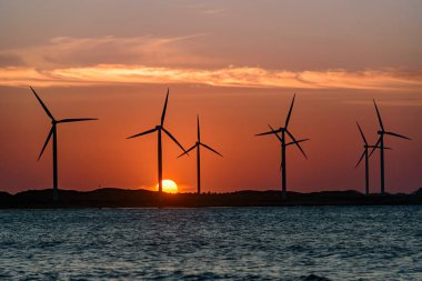 Rüzgar enerjisi. 1 Temmuz 2024 'te Brezilya' nın Icarai de Amontada plajında rüzgar enerjisi çiftliğinin arkasında güneş batıyor..