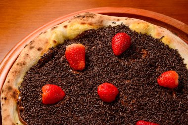 Strawberry pizza with chocolate on wooden table. clipart