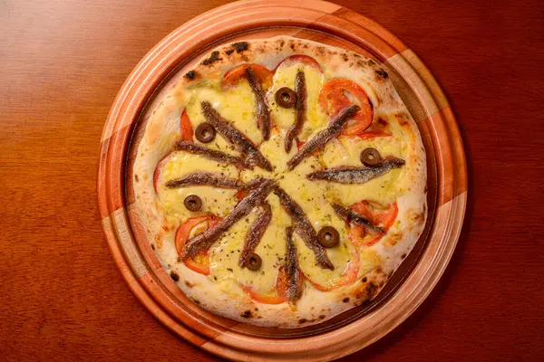 stock image Aliche pizza on wooden table.