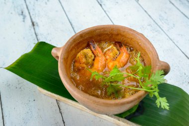 Beyaz boyanmış ahşap masada kil kasede karides çorbası. Brezilya yemekleri kıyıda çok tüketilir..