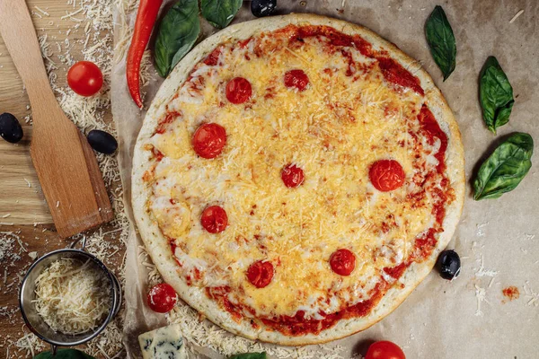 Top view on homemade italian four cheeses pizza. Pizza on rustic wooden background with tomato, cheese, basilic. Copy space. Traditional italian cuisine. Flat lay picture for recipe or menu.