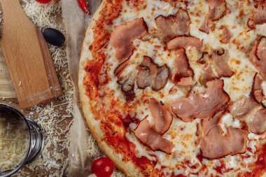 Tavuk peynirli ve pepperonili pizza, bir parçası pakman gibi kesilmiş ve serilmiş, ahşap bir tahtanın üzerinde ve kahverengi bir arka planda. Peynir akış çizgilerini yayar. Yüksek kalite fotoğraf