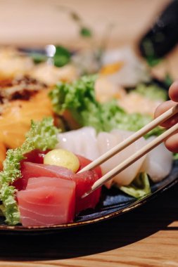 Karışık suşi seti nigiri, rulo ve sashimi geleneksel Japonya siyah suşi yuvarlak tabağında servis edilir. Yüksek kalite fotoğraf