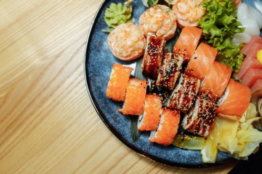 Karışık suşi seti nigiri, rulo ve sashimi geleneksel Japonya siyah suşi yuvarlak tabağında servis edilir. Yüksek kalite fotoğraf