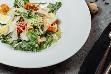 Geleneksel sezar salatası beyaz bir kasede, yapraklı, soslu ve parmesanlı beyaz bir masada. Seçili odak. Yüksek kalite fotoğraf