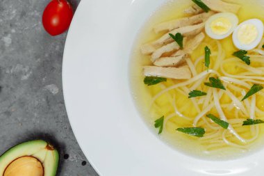 Az yağlı tavuk çorbası, yarı pişmiş yumurta ve maydanozla birlikte beyaz arka planda izole edilmiş cam bir kasede. Yüksek kalite fotoğraf