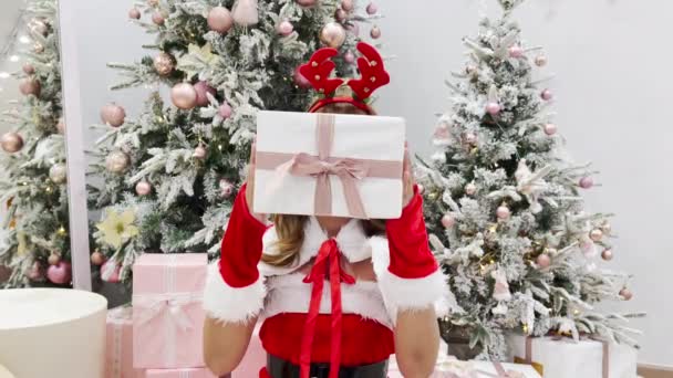 Wanita Muda Yang Mengenakan Santa Claus Memegang Kotak Hadiah Pada — Stok Video