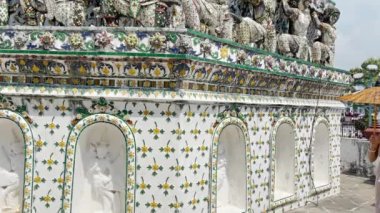 Aksesuarlı Tayland elbisesi giyen genç bir kadın Wat Arun Ratchawararam 'da elinde antika şemsiye ve çanta ile ayakta duruyor. Bangkok, Tayland