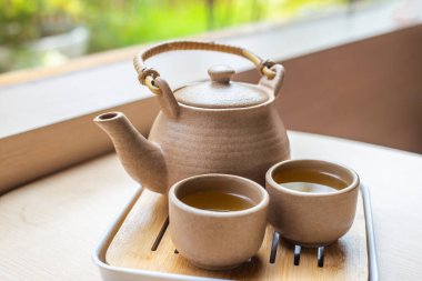 Çaydanlık seti ve geleneksel Japon kupaları bahçedeki ahşap bir masada..