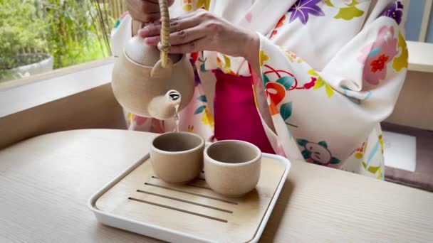 一个穿着日本和服的女人的手把茶倒进杯子里喝水 — 图库视频影像