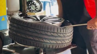 Yetenekli bir tamirci yeni lastikleri alaşımlı lastiklere takıyor..