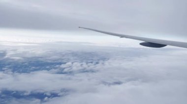 Uçak kanadı, güzel gökyüzü ve bulutlu pencereden manzara.