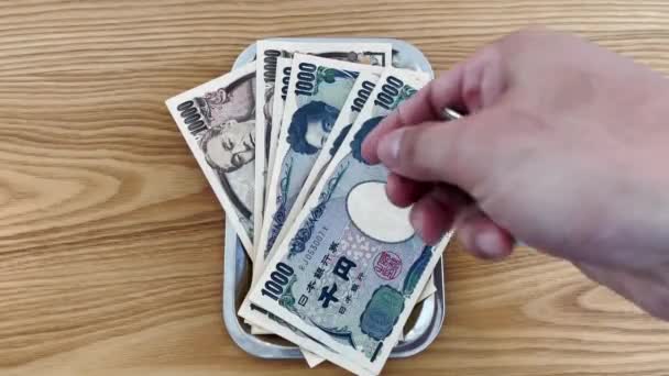 手数着日元 包括钞票和硬币 然后放在盘子里 准备用来购物 经商或旅行 免版税图库视频