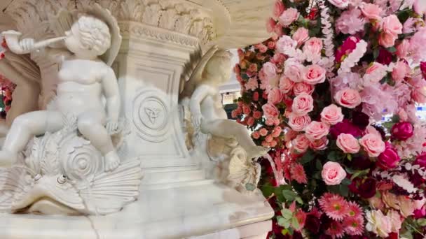 丘比特雕像丘比特雕像掉进池塘里的雕像 用玫瑰和其他花朵装饰 — 图库视频影像