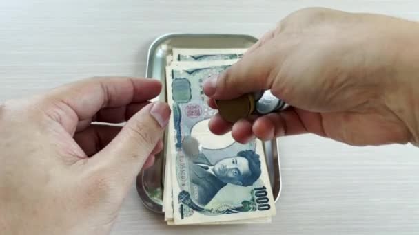 手数着日元 包括钞票和硬币 然后放在盘子里 准备用来购物 经商或旅行 免版税图库视频片段