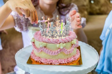 Elin yanan bir mumu tutup doğum günü pastasının içine sokuyor. Yumuşak ve seçili odak