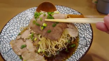 Geleneksel bir Japon yemeği olan duman yayan sıcak ramen pençeli chashu domuz eti maşası yakın plan..