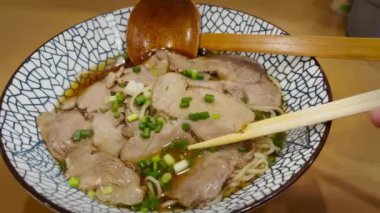 Geleneksel bir Japon yemeği olan duman yayan sıcak ramen pençeli chashu domuz eti maşası yakın plan..