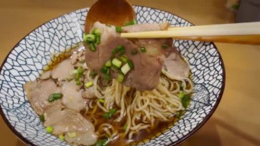 Geleneksel bir Japon yemeği olan duman yayan sıcak ramen pençeli chashu domuz eti maşası yakın plan..
