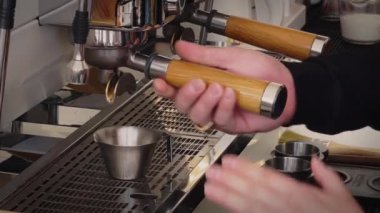 Barista 'nın eli kahve çekirdeklerini gümüş metal bardakla modern bir bira makinesine döküyor..