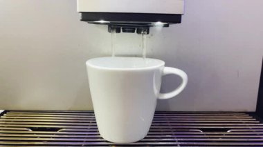Modern bir otomatik kahve makinesi sıcak espresso yumrukluyor. Köpük ve buhar çıkıyor..
