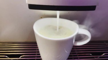 Modern bir otomatik kahve makinesi sıcak espresso yumrukluyor. Köpük ve buhar çıkıyor..