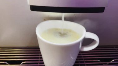 Modern bir otomatik kahve makinesi sıcak espresso yumrukluyor. Köpük ve buhar çıkıyor..