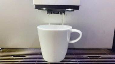 Modern bir otomatik kahve makinesi sıcak espresso yumrukluyor. Köpük ve buhar çıkıyor..