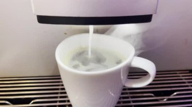 Modern bir otomatik kahve makinesi sıcak espresso yumrukluyor. Köpük ve buhar çıkıyor..