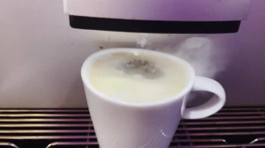 Modern bir otomatik kahve makinesi sıcak espresso yumrukluyor. Köpük ve buhar çıkıyor..