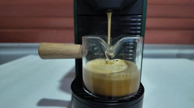 Modern bir otomatik kahve makinesi sıcak espresso yumrukluyor. Köpük ve buhar çıkıyor. Yavaş çekim 