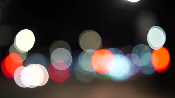 夜の街でブレイクされた車のライトボケ 夜間のヘッドライトと街灯を遮断しました 夜に車のボケのサークルを移動する 輝かしい都市交通の背景 — ストック動画