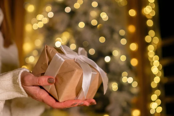 Christmas present in hands or gift box on magical bokeh background. Beautiful Christmas gift boxes with ribbon.