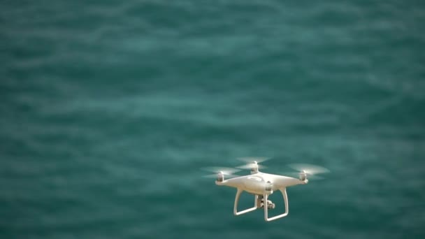白色的无人驾驶飞机在自然界的海洋背景下飞行 无人机在空中盘旋并拍摄视频 飞行直升机无人驾驶飞机 — 图库视频影像