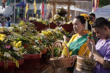 CHIANG MAI THAILAND - 16 Mayıs 2023: Inthakin Festivali veya Sai Khan Dok geleneği Chiang Mai 'nin Chiang Mai, Tayland' daki Wat Chedi Luang 'daki sütununa çiçek sunan vatandaşlardır..