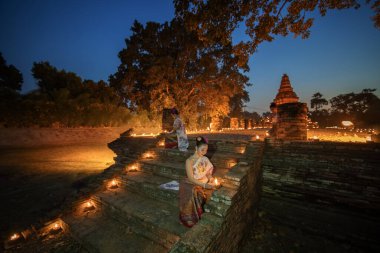 CHIANGMAI - 28 Kasım 2023: Chiang Mai, Tayland 'daki Wiang Kum Kam' da Buda 'ya dua etmek için mum ışığı tutan güzel Asyalı kadınlar.