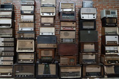 THAILAND - CHIANG-MAI, 31 AUGUST 2024 : Many vintage radios are displayed in front of an old brick wall in an antique shop. clipart