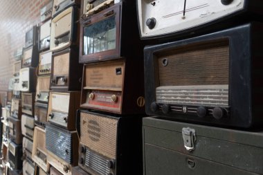 THAILAND - CHIANG-MAI, 31 AUGUST 2024 : Many vintage radios are displayed in front of an old brick wall in an antique shop. clipart