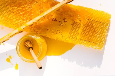 Cam kavanozdaki bal, bal kovanı ve bal peteği beyaz arkaplanı kapatın. Doğal, organik ballı üst görünüm. Arıcılık konsepti. Güneş ışığında bal ürünleri