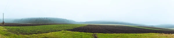 Fog above the agriculture field and forest. Panoramic view on autumn fields and hills. Plowed land