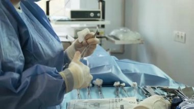Ameliyat için hazırlıklar. Ameliyat aletleri. Ameliyat odasındaki masada birden fazla ameliyat aleti var. Hemşire ellerini lastik eldivenlerle fırçala. Modern tıbbi konsept.