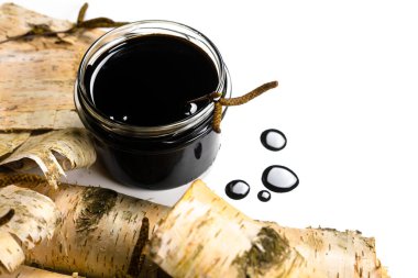Birch katranı ya da zift kabuğu ve huş ağacı kabuğu beyaz arka planda. Ahşap. Huş ağacından sıvı mineral katranı