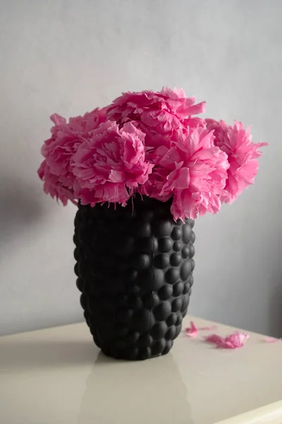 The peony or paeony pink flowers in vase at the shelf. Paeonia \